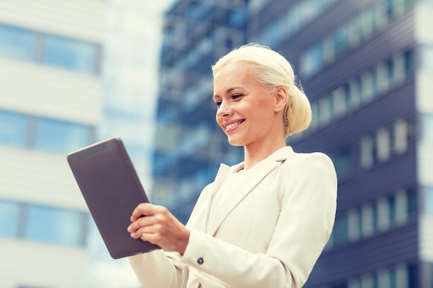 concepto de negocios, educación, tecnología y personas - mujer de negocios sonriente que trabaja con una computadora de tablet pc en la calle de la ciudad