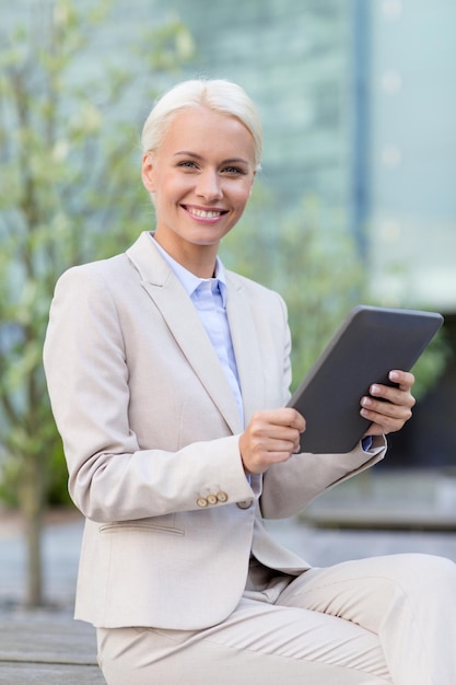 concepto de negocios, educación, tecnología y personas - mujer de negocios sonriente que trabaja con una computadora de tablet pc en la calle de la ciudad