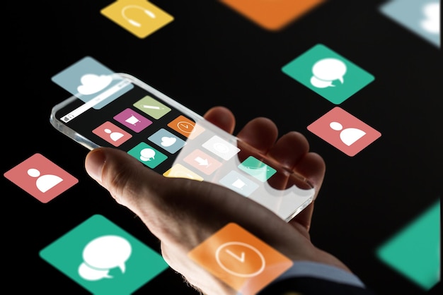 Foto concepto de negocios, multimedia, personas y tecnología moderna: primer plano de la mano de un hombre de negocios con un teléfono inteligente transparente con iconos de menú en la pantalla sobre fondo negro