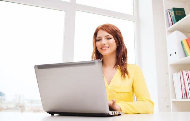 concepto de negocios, oficina, escuela y educación - mujer de negocios sonriente con computadora portátil en la oficina