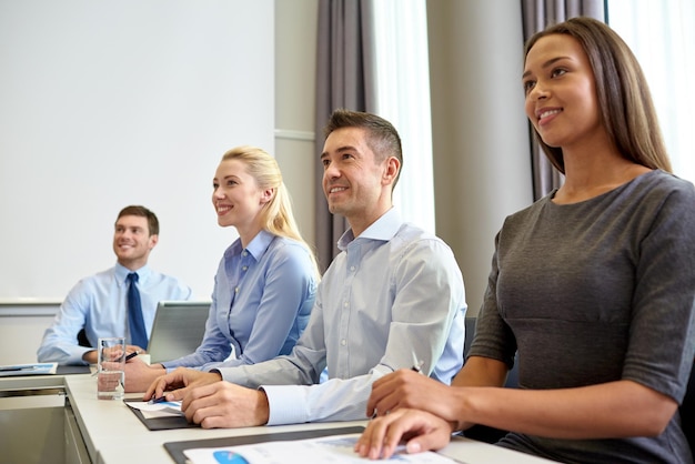 concepto de negocios, personas y conferencias - reunión sonriente del equipo de negocios en la presentación en la oficina