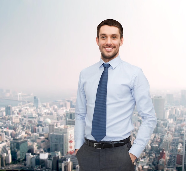 El concepto de negocios y personas: un joven y apuesto hombre de negocios sonriente sobre el fondo del paisaje urbano