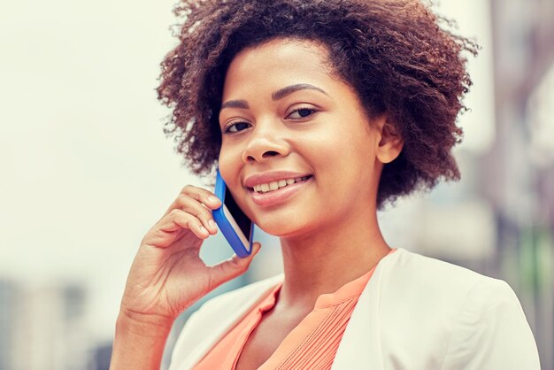 concepto de negocios y personas - joven empresaria afroamericana sonriente en la ciudad