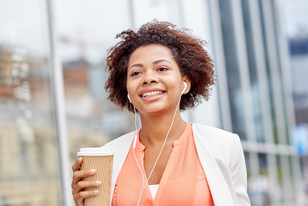 concepto de negocios y personas - joven empresaria afroamericana sonriente con taza de café en la ciudad