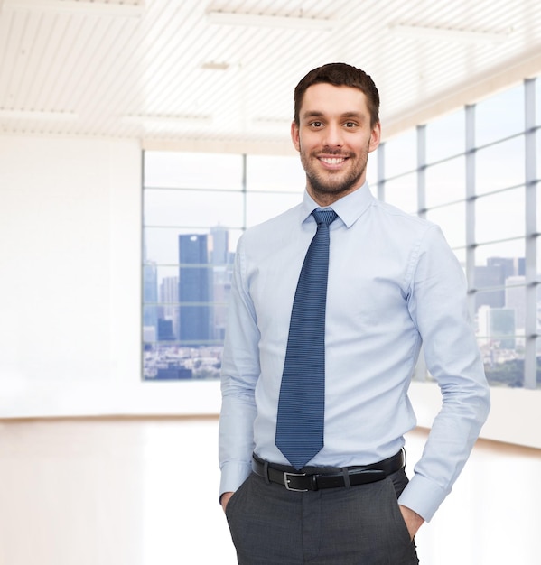 Foto concepto de negocios, personas y oficina - joven hombre de negocios feliz sobre la sala de oficina o el nuevo fondo del apartamento