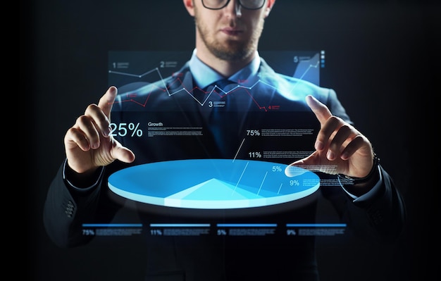 concepto de negocios, personas, tecnología y ciberespacio: cierre de un hombre de negocios con traje que trabaja con gráficos en proyección de pantalla virtual sobre fondo negro