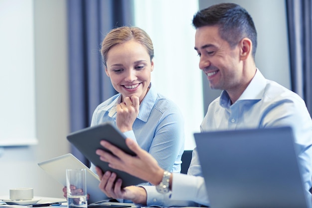 concepto de negocios, personas y tecnología - equipo de negocios sonriente con computadoras tablet pc reunidas en la oficina