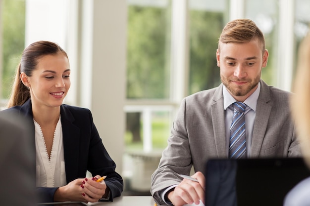 concepto de negocios, personas y tecnología - equipo de negocios sonriente con reunión de computadora portátil en la oficina