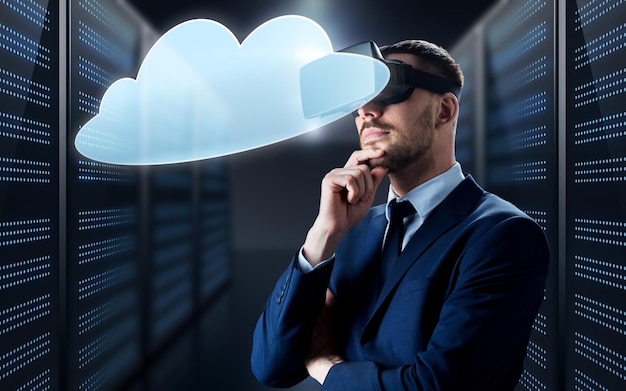 concepto de negocios, personas y tecnología - hombre de negocios en auriculares de realidad virtual con icono de computación en la nube sobre el fondo de la sala de servidores futurista