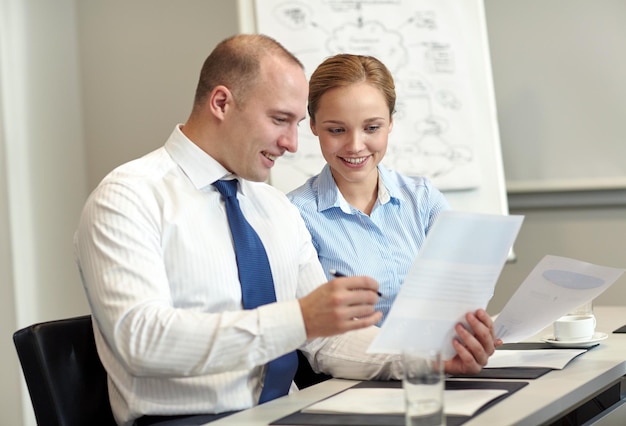 concepto de negocios, personas y trabajo en equipo - equipo de negocios sonriente con documentos reunidos en la oficina