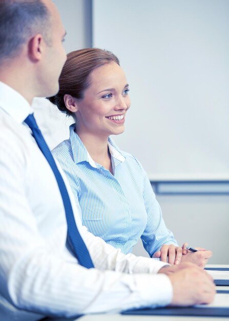 concepto de negocios, personas y trabajo en equipo - hombre de negocios sonriente y mujer de negocios reunidos en el cargo