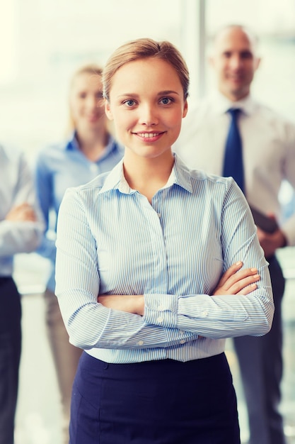 concepto de negocios, personas y trabajo en equipo - mujer de negocios sonriente con un grupo de empresarios en el cargo