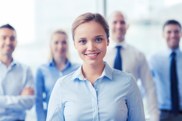 concepto de negocios, personas y trabajo en equipo - mujer de negocios sonriente con un grupo de empresarios en el cargo