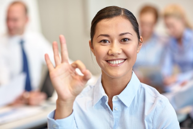 concepto de negocios, personas y trabajo en equipo - mujer de negocios sonriente con un grupo de empresarios reunidos en el cargo