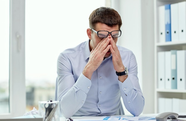 concepto de negocios, personas y trabajo - hombre de negocios cansado con anteojos en la oficina