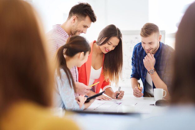 concepto de negocios, startups, educación y personas - equipo de arquitectos creativos felices o estudiantes con planos trabajando en la oficina