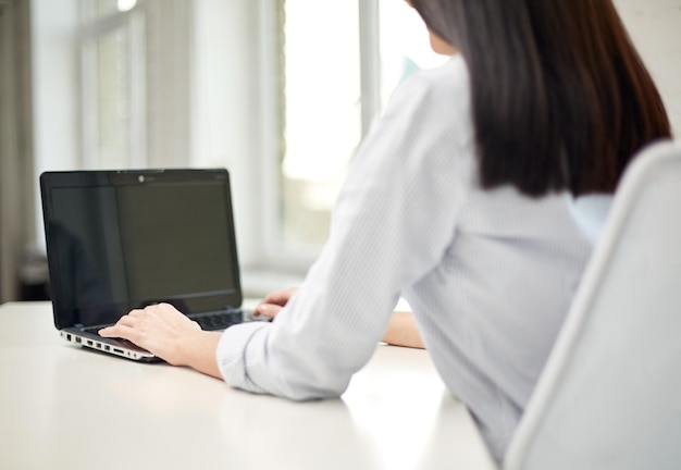 concepto de negocios, tecnología, comunicación y personas: cierre de una mujer escribiendo en una computadora portátil en la oficina o en el hogar