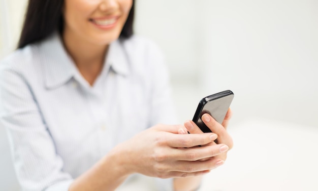 concepto de negocios, tecnología y personas: cierre de mensajes de texto de manos de mujer en el teléfono inteligente