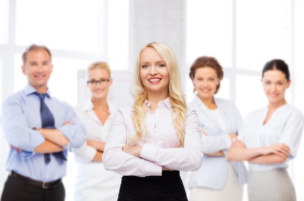 concepto de negocios, trabajo en equipo y personas - mujer de negocios sonriente, estudiante o secretaria sobre la oficina y el fondo de un grupo de colegas