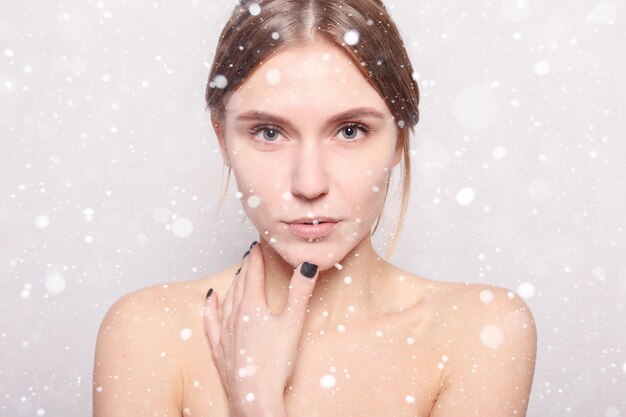 Concepto de nieve, invierno, navidad, belleza, cuidado de la piel y personas - Spa Woman. Hermosa chica después del baño tocando su rostro. Bella dama con toalla en la cabeza, tocando su suave piel. sobre fondo de nieve