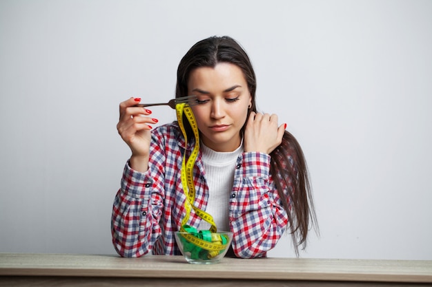 Concepto de niña delgada con un plato lleno de cinta