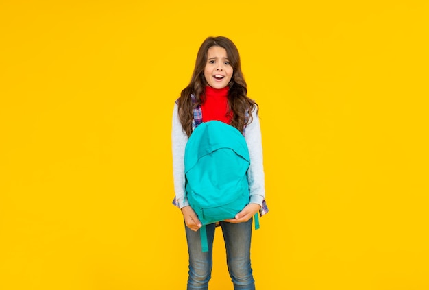 Concepto de niño de educación en ropa casual sobre fondo amarillo 1 de septiembre niño de infancia feliz con mochila escolar niña adolescente confundida llevar mochila de regreso a la escuela día del conocimiento