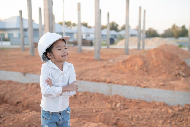 Concepto de niño ingeniero Niña asiática usa uniforme de ingeniero trabajando en el sitio del edificio