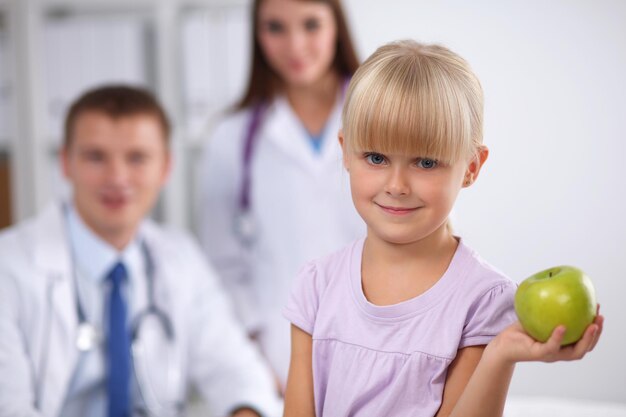 Concepto de niño y medicina doctora dando una manzana a una niña sonriente