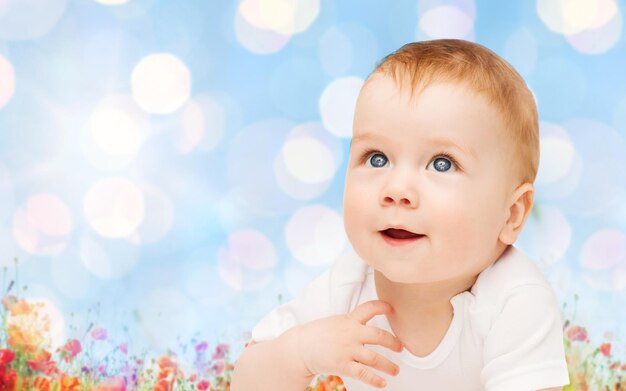 concepto de niños, personas, infancia y edad - hermoso bebé feliz sobre luces azules y fondo de campo de amapola