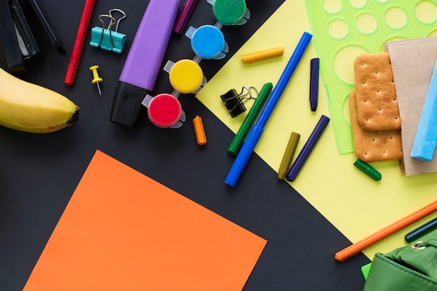 Concepto de nuevo a la escuela ver la línea de tiza papelería galletas sobre fondo negro.