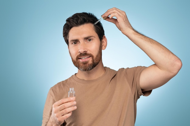 Foto concepto de nutrición de la piel guapo hombre barbudo de mediana edad que aplica suero esencial orgánico en la cara