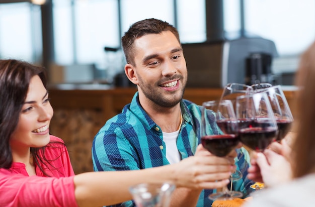 concepto de ocio, celebración, bebidas, gente y vacaciones - pareja feliz y amigos tomando copas de vino en el restaurante