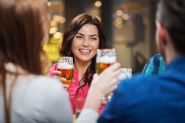 Concepto de ocio, comida, comida y bebida, personas y vacaciones: amigos sonrientes cenando y bebiendo cerveza en un restaurante o pub