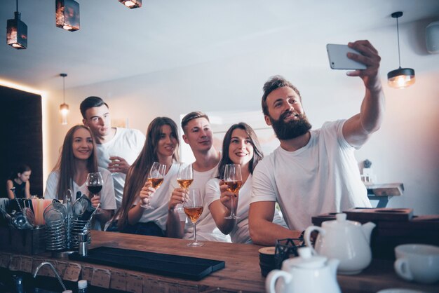 Concepto de ocio y comunicación. Grupo de amigos sonrientes felices disfrutando de bebidas y hablando en el bar o pub