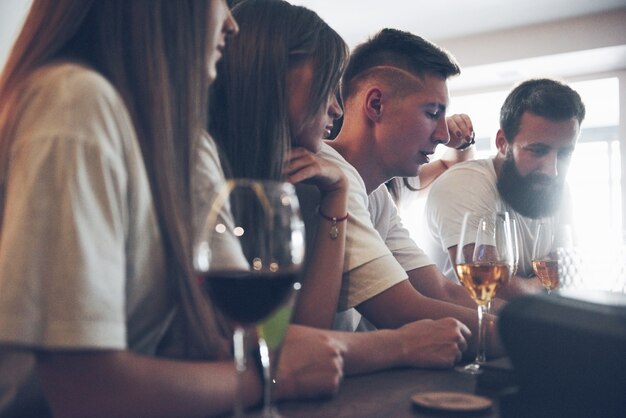 Concepto de ocio y comunicación. Grupo de amigos sonrientes felices disfrutando de bebidas y hablando en el bar o pub