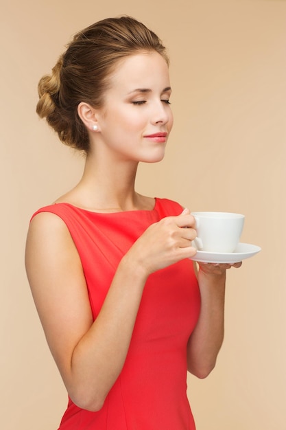 concepto de ocio, felicidad y bebida - mujer sonriente vestida de rojo con una taza de café