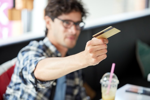 concepto de ocio, gente, pago y finanzas - hombre pagando con tarjeta de crédito en el café