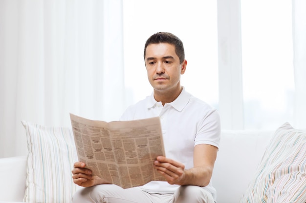 concepto de ocio, información, personas y medios de comunicación - hombre leyendo el periódico en casa