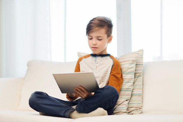 concepto de ocio, niños, tecnología y personas - chico con tablet pc en casa