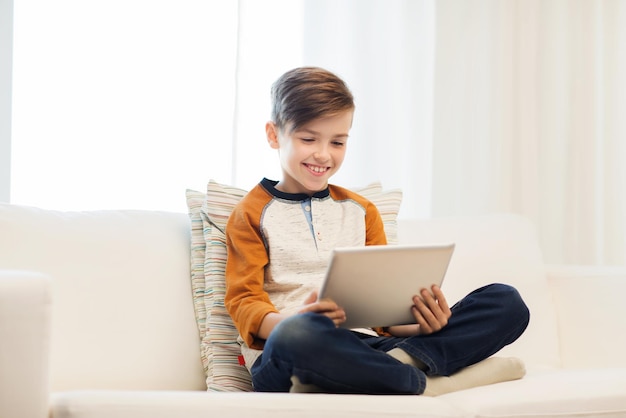 concepto de ocio, niños, tecnología y personas - niño sonriente con tablet pc en casa