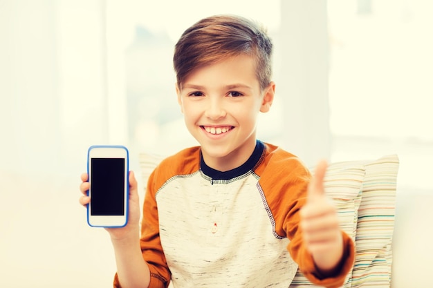 concepto de ocio, niños, tecnología, publicidad y personas - niño sonriente con smartphone en casa