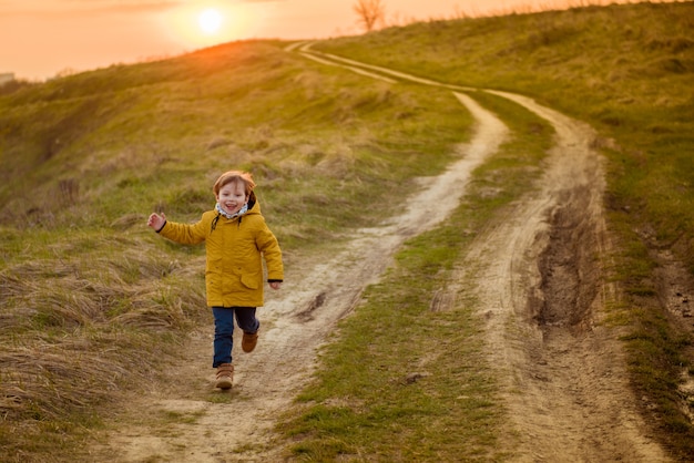 Concepto de ocio y personas de la infancia - niño feliz corriendo en el campo del parque de otoño