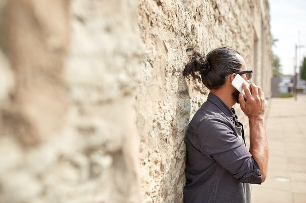 concepto de ocio, tecnología, comunicación y personas: cierre de un hombre llamando y hablando por teléfono inteligente en la calle