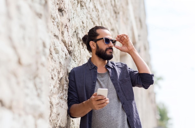 concepto de ocio, tecnología, comunicación y personas - hombre con teléfono inteligente en la pared de piedra