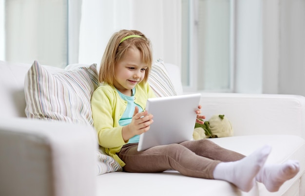 concepto de ocio, tecnología y niños - niña pequeña con tablet en casa