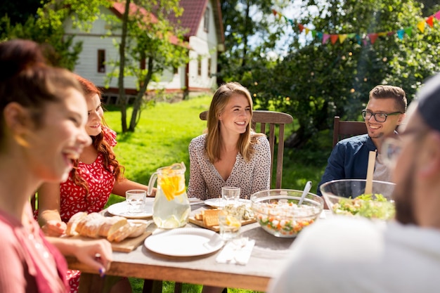 concepto de ocio, vacaciones, comida, gente y comida - amigos felices cenando en la fiesta del jardín de verano