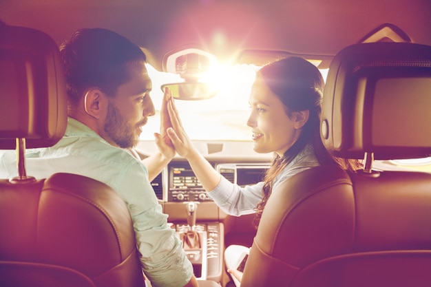 concepto de ocio, viaje por carretera, viajes y personas - hombre y mujer felices haciendo gestos altos y conduciendo en coche