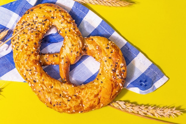 Concepto de Oktoberfest: galletas saladas en una servilleta tradicional. Luz dura de moda, sombra oscura. Espiguillas secas, fondo amarillo pastel, cerrar