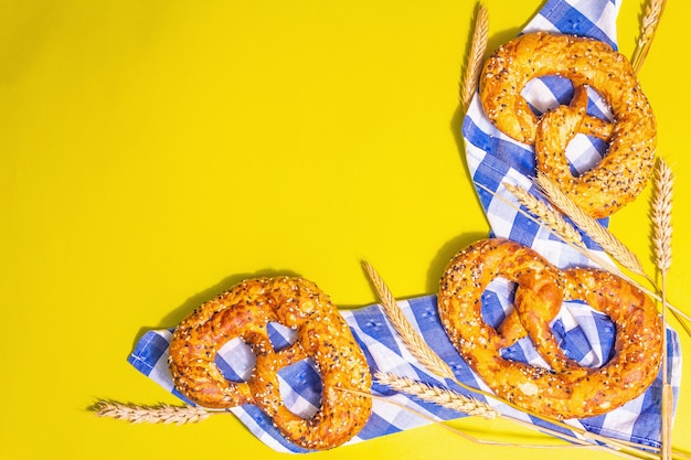 Concepto de Oktoberfest: galletas saladas en una servilleta tradicional. Luz dura de moda, sombra oscura. Espiguillas secas, fondo amarillo pastel, lugar para el texto