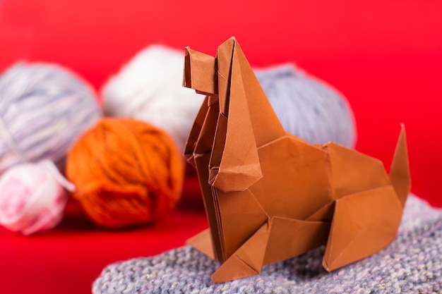 Concepto de origami de Papercraft de un hogar acogedor: un perro con bolas de lana se sienta en un latigazo. Papel de arte hecho a mano de cerca